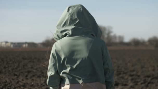 Vista trasera de un femaler solitario en una capucha vagando por el campo — Vídeos de Stock