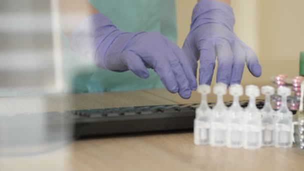 Desktop of a medical worker. Computer keyboard, medication. The doctor s hands are protected by disposable gloves. — Stock Video