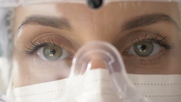 Egy védőszemüveges női orvos szemei. Komoly nézés. Közelkép. — Stock videók