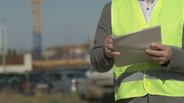 Byggaren gör anteckningar. Mot bakgrund av ett föremål under uppförande. — Stockvideo