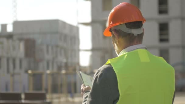 Il costruttore fa delle entrate. Vista posteriore. Contro l'edificio in costruzione . — Video Stock