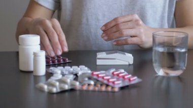 Kadın ilaç alıyor ve ilaç kesicisi kullanıyor. Baş ağrısı ve ateş için ilaç alıyor, baş ağrısını tedavi ediyor.