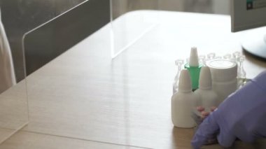 Koruyucu lateks eldivenlerle müşteriye servis yapan eczacı. Eczacının işyeri plastik şeffaf bir bölme ile korunur..