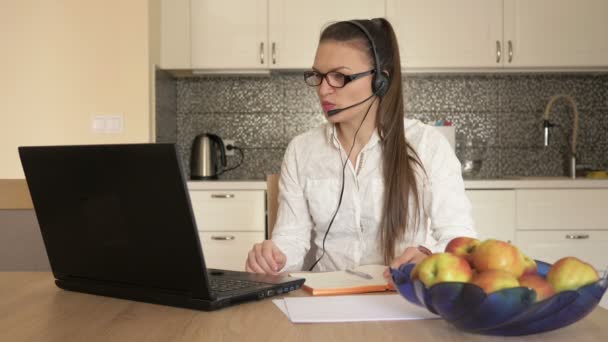 Γυναίκα με ακουστικά μπροστά από το laptop στο τραπέζι, online συμβουλευτική. Τηλεεργασία. — Αρχείο Βίντεο