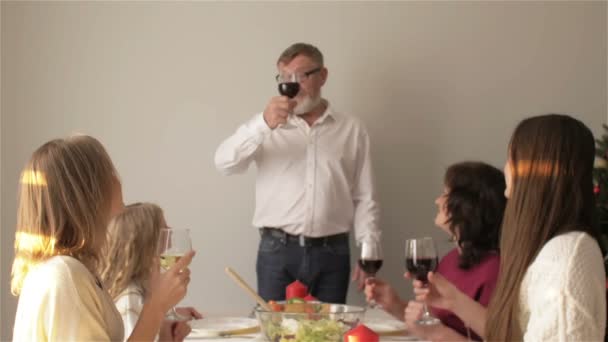 Família sentada em torno de uma mesa, comendo, comunicando e se divertindo durante o jantar em família. Brindar em família na mesa de jantar em casa — Vídeo de Stock