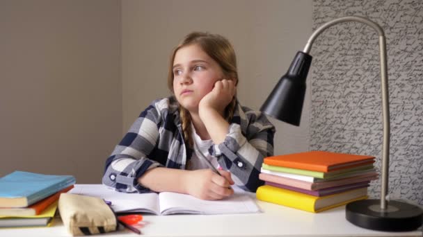 Schoolmeisje droomt terwijl ze huiswerk maakt. Meisje zit aan een bureau, steekt haar hoofd met. — Stockvideo