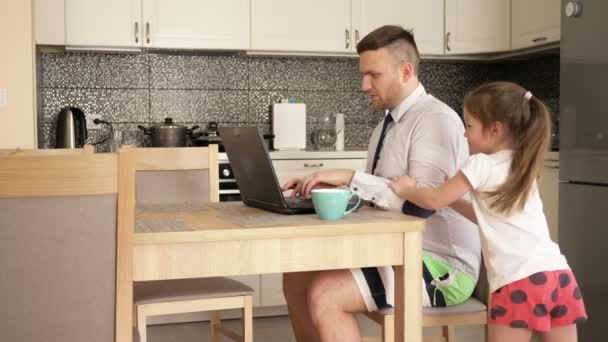 Young man works at the computer at home because of the quarantine. Little daughter is stopping him from working. — Stock Video