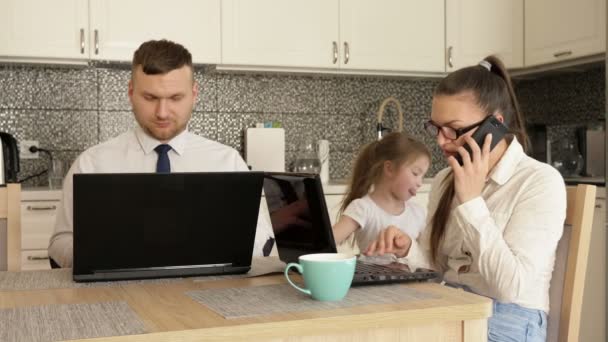 Junge Eheleute sind aufgrund von Quarantäne gezwungen, zu Hause zu arbeiten. Kleine Tochter langweilt sich, sie will spielen, also hindert sie ihre Eltern daran zu arbeiten. — Stockvideo