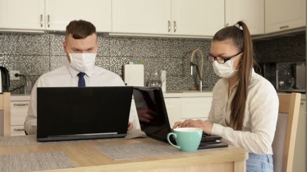 Arbeiten Sie aus der Ferne. Junges Paar musste wegen Quarantäne zu Hause arbeiten. Auf den Gesichtern sind medizinische Masken. Das Kind braucht die Aufmerksamkeit der Eltern. — Stockvideo