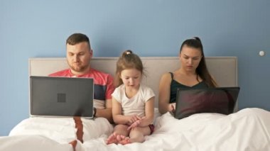 İnternet işi. Yatakta yatarken dizüstü bilgisayarlarla çalışan genç evli bir çift. Küçük kız çok sıkılmış, ebeveyn ilgisine ihtiyacı var..
