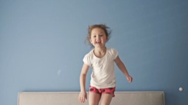 Neşeli küçük kız uyandıktan sonra yatağa atlıyor..