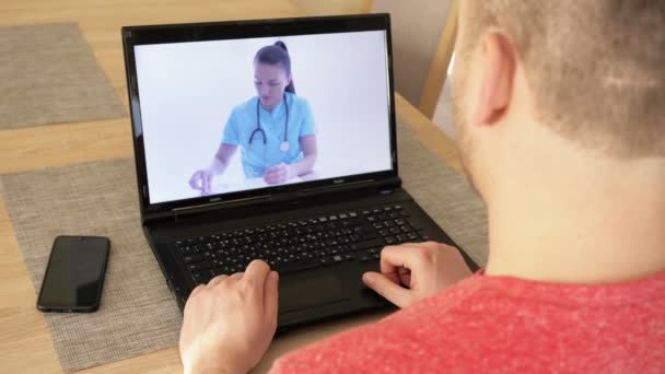 Telemedicin. Ung man som har videochatt med läkare på bärbar dator hemma. — Stockvideo