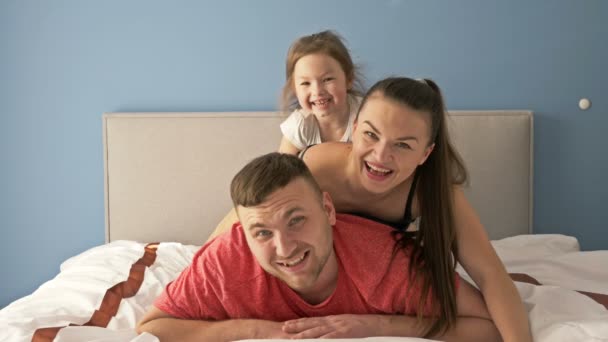 快乐的家庭早晨。爸爸，妈妈和小女儿在床上玩. — 图库视频影像
