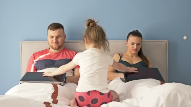 Trabalho online em casa. Casal jovem trabalhando com laptops enquanto deitado na cama. A menina está muito entediada, ela requer atenção dos pais . — Vídeo de Stock