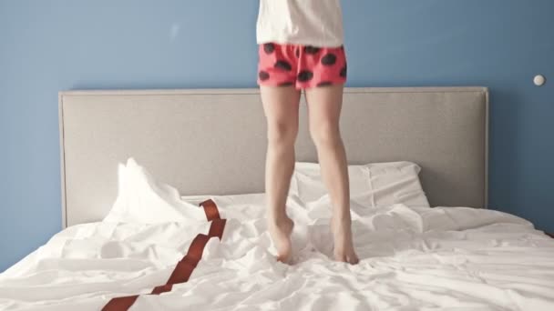 En fräck liten flicka som har kul när hon hoppar i säng.. — Stockvideo