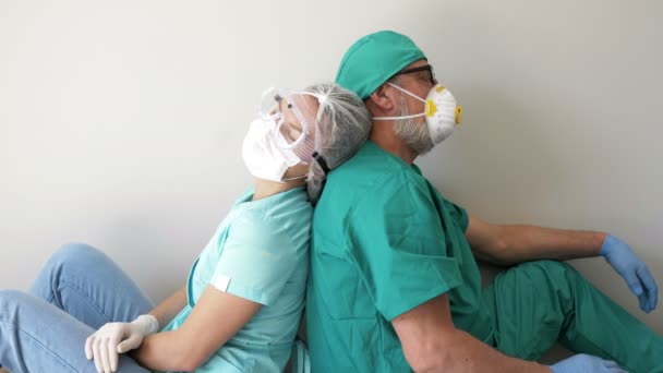 精疲力尽的医护人员背靠背地坐在地板上休息. — 图库视频影像