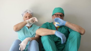 İki doktor bütün gün çalıştıktan sonra koridorda yorgun oturuyorlar..