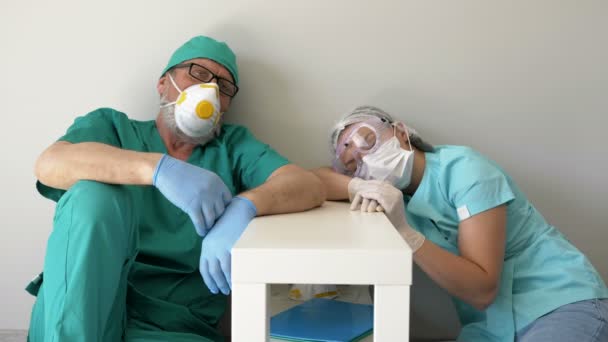 Médico y enfermera cansados están descansando sentados en el suelo en un pasillo del hospital . — Vídeos de Stock