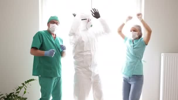 Drie dokters dansen tijdens een pauze in een ziekenhuisgang. Optimisme tijdens de Covid-19 epidemie. — Stockvideo