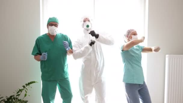 Egy csapat orvos védőruhában táncol a kórházi folyosó szünetében. kovid-19. — Stock videók