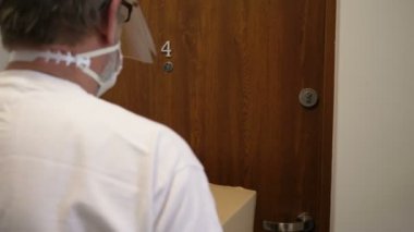 Koruyucu maskeli kurye paketi teslim eder, tıbbi maskeli müşteri kutuyu alır. Karantina, hastalık salgını, koronavirüs covid-19 salgını altında teslimat hizmeti.