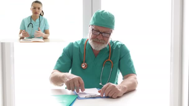 Video conference. Elderly doctor advises a young colleague. — Stock Video