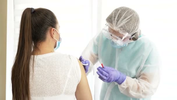 Krankenschwester im Schutzanzug injiziert Impfstoff an Patientin. Stimulation der Immunität zur Minimierung des Risikos einer Coronavirus-Infektion. — Stockvideo