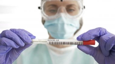 Coronavirus COVID-19 NP OP örnek test kiti, burun toplama ekipmanı tutan bir tıp çalışanı. Sonuç pozitif..