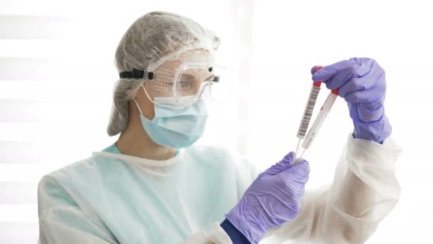 Vrouwelijke laboratoriumtechnicus met twee coronavirus COVID-19 testkit. — Stockvideo