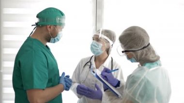Koruyucu üniformalı iki doktor bir şeyi tartışıyor ve hemşireye talimat veriyor. Covid 19.
