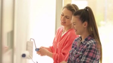 İki aktif kadın odanın duvarlarını boyuyor ve eğlenceli bir sohbet yapıyorlar..