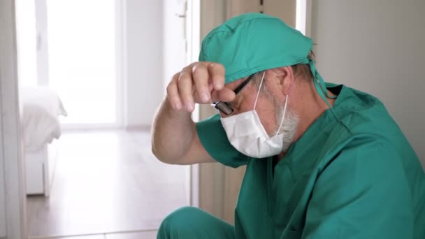 Bitkin düşmüş yaşlı doktor hastane koridorunda dinlenmek için yere oturdu.. — Stok video