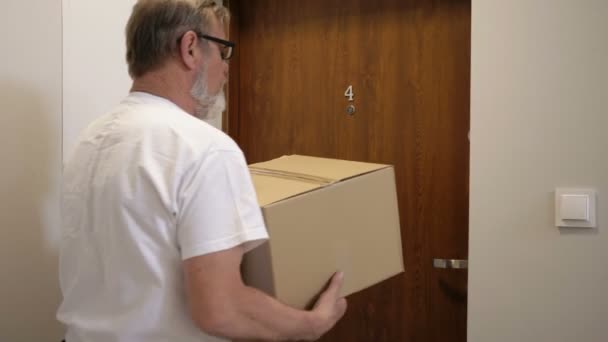 Кур'єр доставляє посилку, молода жінка отримує коробку. Служба доставки. — стокове відео