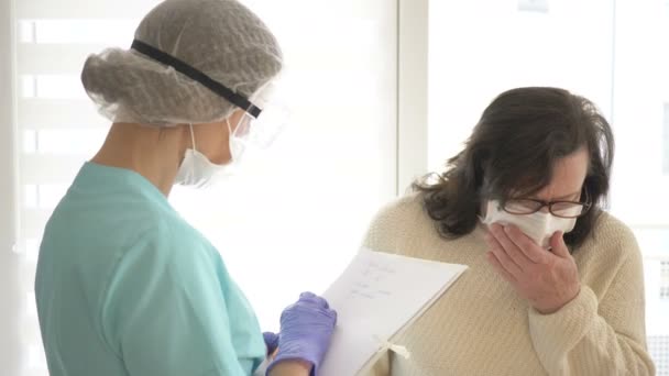 O enfermeiro mede a temperatura de um paciente com suspeita de infecção por coronovírus. O resultado é registrado no log . — Vídeo de Stock