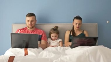 Yatakta yatarken dizüstü bilgisayarlarla çalışan genç evli bir çift. Küçük kız çok sıkılmış, ebeveyn ilgisine ihtiyacı var. Ebeveynler bebeği anlar..