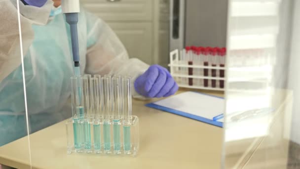 Asisten laboratorium yang mengatur pereaksi ke dalam tabung reaksi dengan darah.. — Stok Video