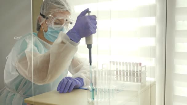 Bloedonderzoek in het laboratorium. Laboratoriumtechnicus in beschermende kleding die met de dispenser werkt. — Stockvideo