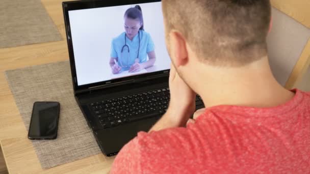 Telemedicin. Ung man som har videochatt med läkare på bärbar dator hemma. — Stockvideo