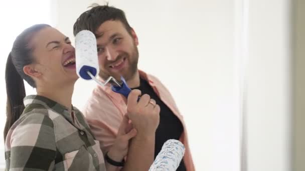 Beautiful couple paint the walls in a new apartment, laughing and having fun. Young family makes repairs in their new flat — Stock Footage Beautiful couple paint the walls in a new apartment, laughing and having fun. Young family makes repairs in their new flat Stock Video