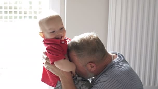 Grandfather is having fun with his little grandson. The kid took off his glasses from his grandfather. — Stock Video