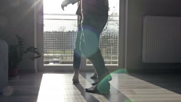 Las piernas masculinas y femeninas están bailando divertido en casa en el fondo de la ventana. La alegría del amor y del movimiento . — Vídeos de Stock