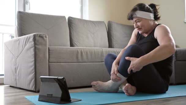 Actieve vrouw van middelbare leeftijd beoefent thuis yoga. Een gezonde levensstijl in quarantaine in zelf-isolatie coronavirus pandemie. — Stockvideo