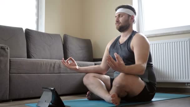 Young man practices yoga at home. Laptop is next to him. Online sport. Sport in quarantine at home. — Stock Video