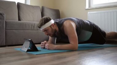 Paspasın üzerinde yoga egzersizi yapan genç bir adam, tahta. Evde karantinada spor. Çevrimiçi ders.
