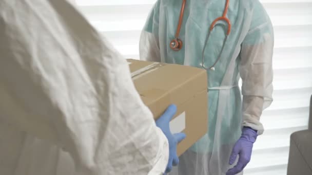 Der Freiwillige gibt dem Arzt Boxen mit den notwendigen Medikamenten und persönlicher Schutzausrüstung. Wohltätigkeit während der COVID-19-Epidemie. — Stockvideo