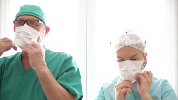 Доктор и медсестра надели медицинские маски. Готовимся к приему пациентов. COVID-19 . — стоковое видео
