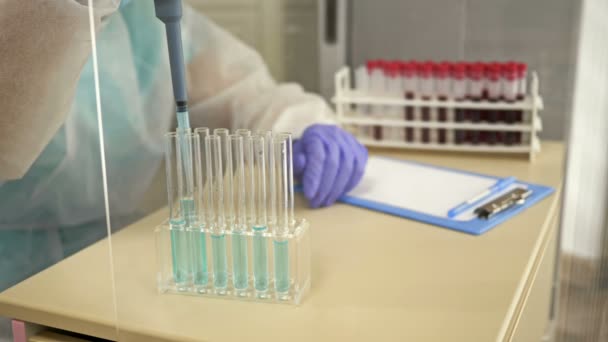 Labortechniker pipettiert das Reagenz in ein Reagenzglas mit Blut. — Stockvideo