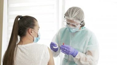 Koruyucu giysili hemşire hastaya aşı aşısı yapıyor. Koronavirüs enfeksiyonu riskini en aza indirmek için bağışıklık uyarımı.