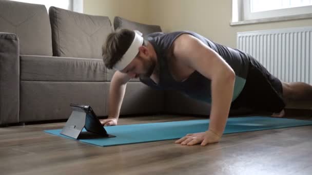 Hombre de mediana edad practica deportes en casa en cuarentena. Deporte en línea. Estilo de vida saludable . — Vídeo de stock