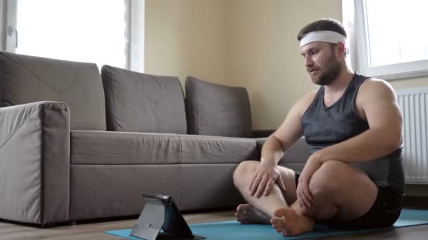 Grasso uomo di mezza età comunica con il suo istruttore di yoga online. La possibilità di praticare sport senza uscire di casa . — Video Stock